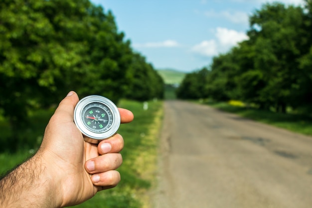 Tient une boussole sur le fond de la route et des arbres