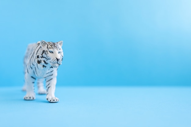 Le tigre, symbole de l'année 2022. tigre blanc en plastique de figure de jouet sur un fond bleu. espace pour le texte