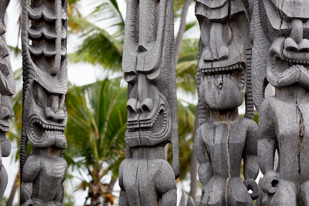 Photo tiki en bois sculpté avec palmiers dans le dos