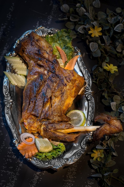 Tikka de cuisse de poulet barbecue avec salade et sauce à la menthe servi dans un plat isolé sur fond sombre vue de dessus