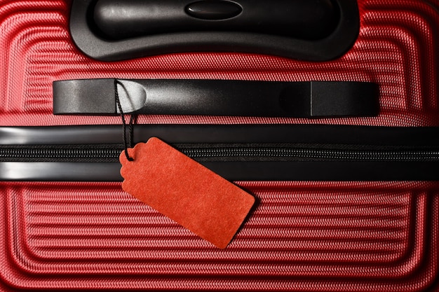 Étiquette d'assurance voyage liée à une élégante valise rouge