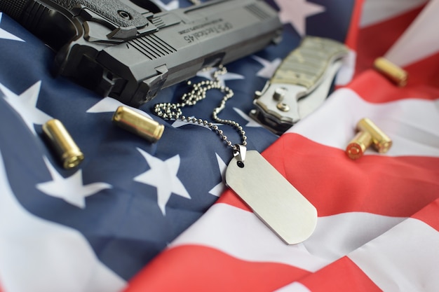 Étiquette de chien de l'armée avec des balles de 9 mm et un pistolet se trouvant sur le drapeau des États-Unis plié
