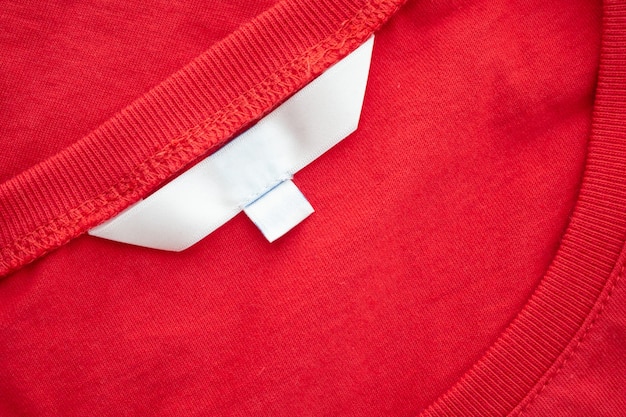 Étiquette de vêtement blanc blanc sur nouveau fond de texture de tissu chemise en coton rouge