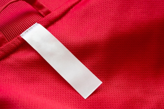 Étiquette de vêtements blanc vierge sur fond de texture jersey rouge