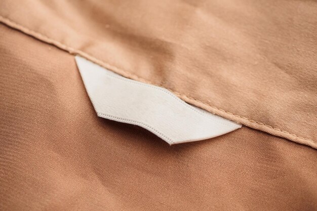 Étiquette de vêtements blanc vierge sur fond de texture de tissu marron