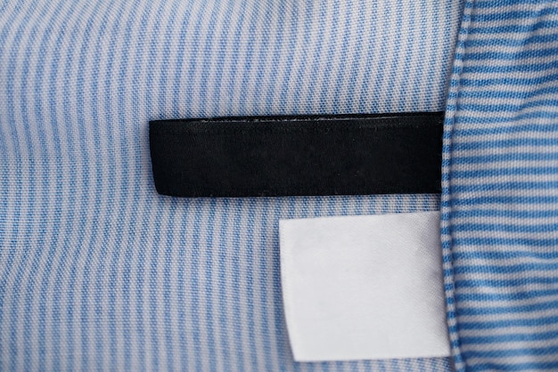 Étiquette de vêtements noir et blanc vierge sur fond de texture de tissu bleu