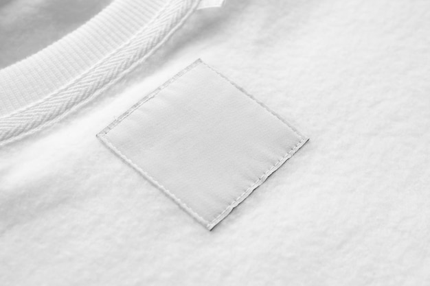 Étiquette de vêtements de soin de lessive blanche vierge sur fond de texture de tissu