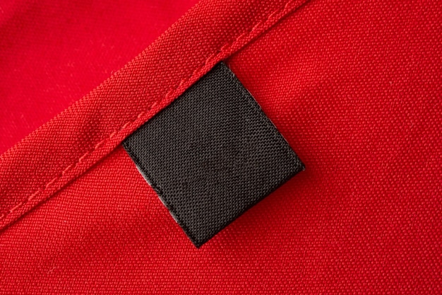 Étiquette de vêtements de soin de lessive noire vierge sur fond de texture de tissu rouge