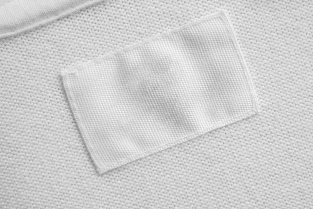 Étiquette de vêtements de soins du linge blanc blanc sur fond de chemise en coton