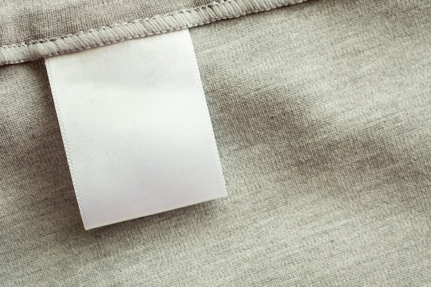 Étiquette de vêtements de soins du linge blanc blanc sur fond de texture de tissu gris
