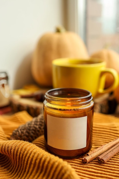 Étiquette vierge sur une bougie allumée dans un espace de décoration d'automne pour votre logo