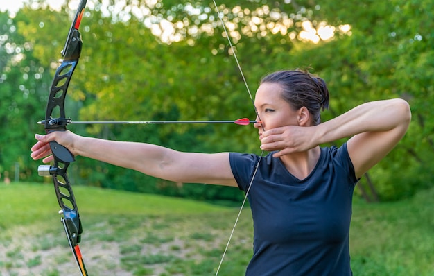 Tir à l'arc, jeune femme avec une flèche dans un arc concentré sur la cible