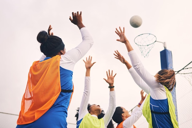 Tir au but de netball et remise en forme d'un groupe d'athlètes féminines sur un terrain de sport extérieur Viser le jeu sportif et le défi de match d'une personne noire avec un ballon faisant de l'exercice et s'entraînant dans une compétition