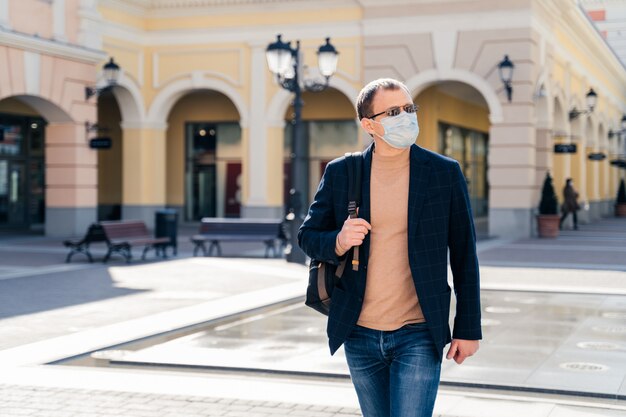 Tir extérieur d'un homme sérieux marche avec sac à dos et porte un masque médical