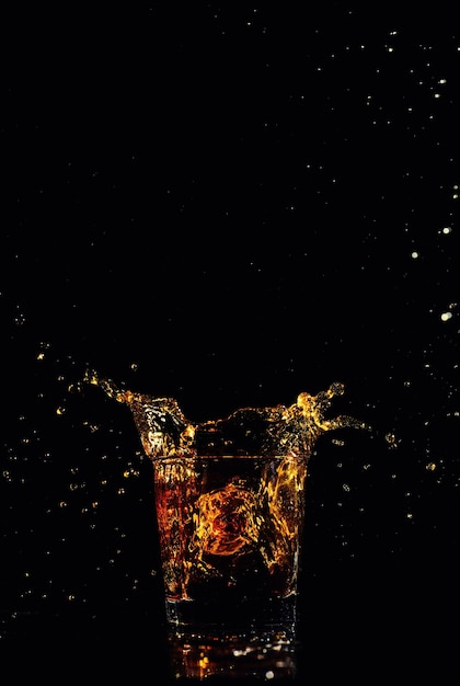 Tir isolé de whisky avec splash sur fond noir