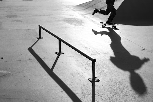 Tir en niveaux de gris d'un homme faisant des tours avec une planche à roulettes