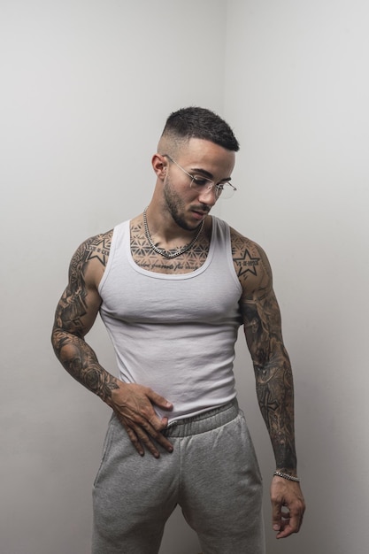 Tir vertical d'un beau jeune homme européen tatoué avec un fond blanc