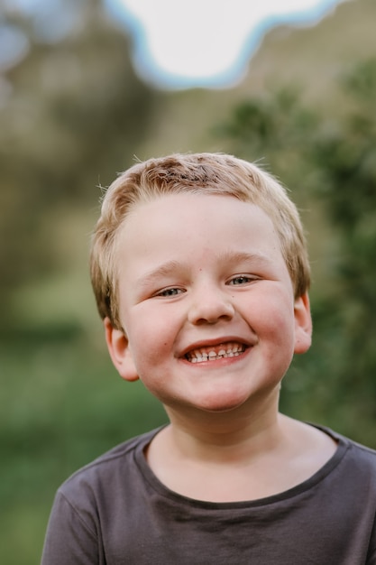 Tir vertical d'un enfant blond souriant mignon