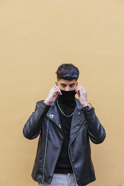 Tir vertical d'un jeune homme portant un manteau en cuir avec un col roulé, collier