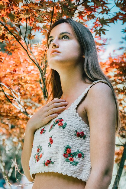 Tir Vertical D'une Jolie Fille Aux Cheveux Longs Bruns Devant L'arbre Avec Des Feuilles Jaunes