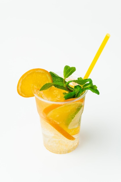 Tir vertical d'une limonade orange fraîche dans un verre en plastique à emporter avec de la menthe