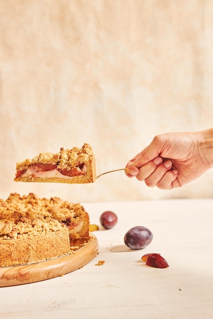 Tir vertical d'une main prenant une tranche de délicieux gâteau aux prunes