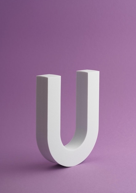 Photo tir vertical de l'objet white letter u sur fond de couleur violet avec espace de copie