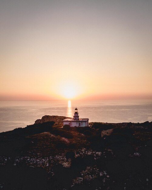 Tir vertical d'un phare sur une falaise au bord de la mer au coucher du soleil