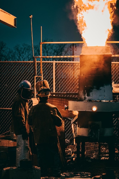 Tir vertical de travailleurs industriels adultes en uniformes fondant du métal dans une usine