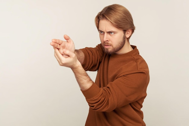 Tir visé. Portrait d'un homme barbu concentré concentré pointant du doigt le geste du pistolet vers la cible, menaçant de tuer