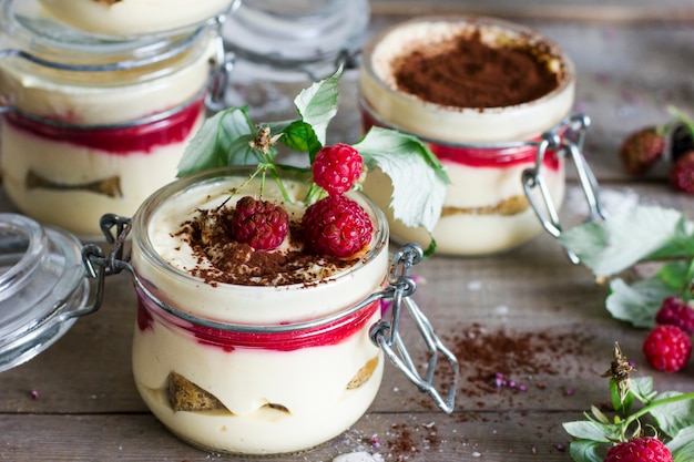 Tiramisu de dessert fait maison avec des framboises dans le bocal en verre sur fond en bois ancien