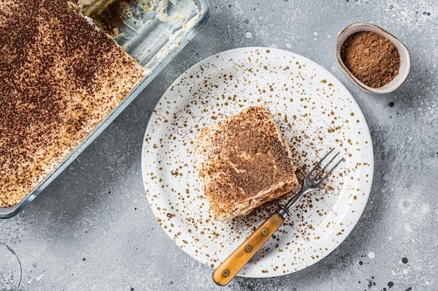 Tiramisu dessert italien garni de cacao sur une assiette. Fond gris. Vue de dessus.