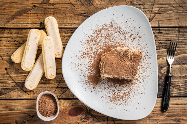 Tiramisu gâteau italien au cacao dans une assiette. Fond en bois. Vue de dessus.