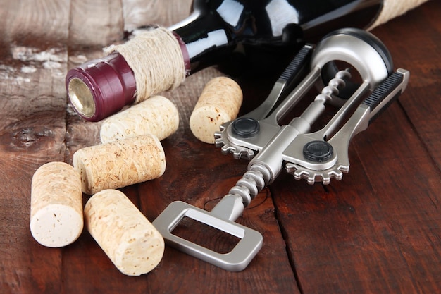 Photo tire-bouchon avec bouchons de vin et bouteille de vin sur table en bois agrandi