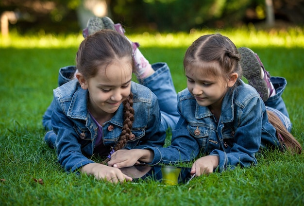 Tiré de deux petites sœurs avec tablette allongée sur l'herbe au parc