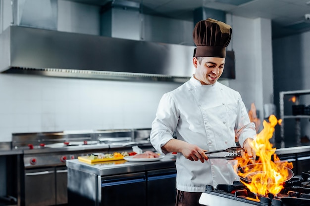 Tiré d'un jeune chef masculin flambant dans une cuisine professionnelle