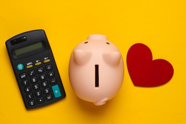 Tirelire, calculatrice et coeur sur jaune