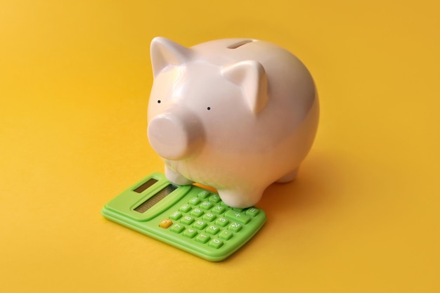 Une tirelire et une calculatrice à côté un symbole pour calculer les finances