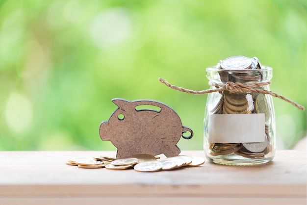 Tirelire et pièces d&#39;or en pot de verre sur table en bois