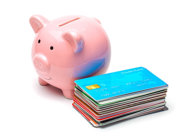 Tirelire rose et cartes de crédit dans une pile isolée sur fond blanc Comment économiser de l'argent