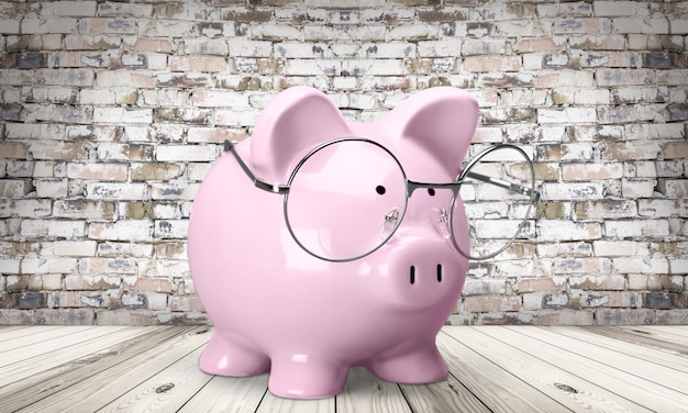Tirelire rose avec des lunettes sur fond de mur de briques, concept d'économie d'argent intelligent
