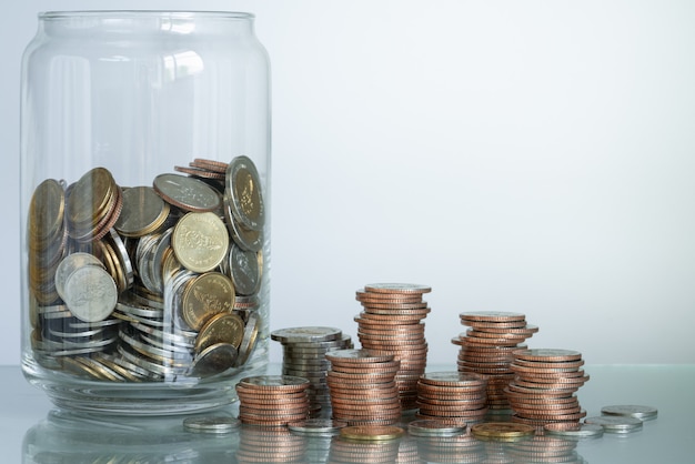 Tirelire en verre et piles de pièces sur table avec espace de copie pour le concept d'entreprise et d'épargne.