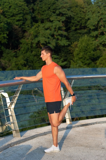 Étirements après l'entraînement. L'homme sportif attrape la cheville avec la main. Étirement du quad debout. Routine d'étirement. Étirement statique. La jambe s'étire.