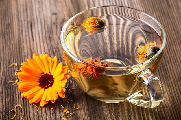 Tisane au Calendula (Marigold) dans une tasse en verre transparent avec des fleurs séchées