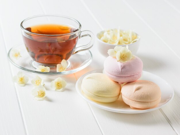 Tisane, un bol de guimauves et de fleurs de jasmin sur un tableau blanc. La composition du petit déjeuner du matin.