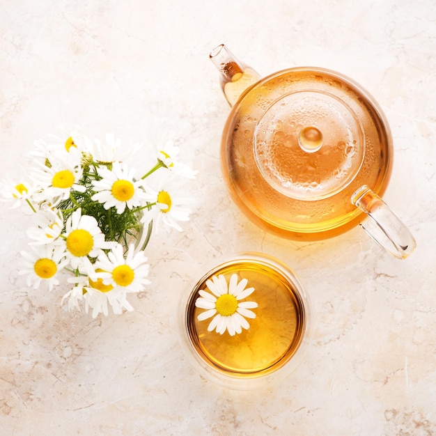 Tisane à la camomille dans une théière et une tasse sur une vue de dessus de fond en pierre beige