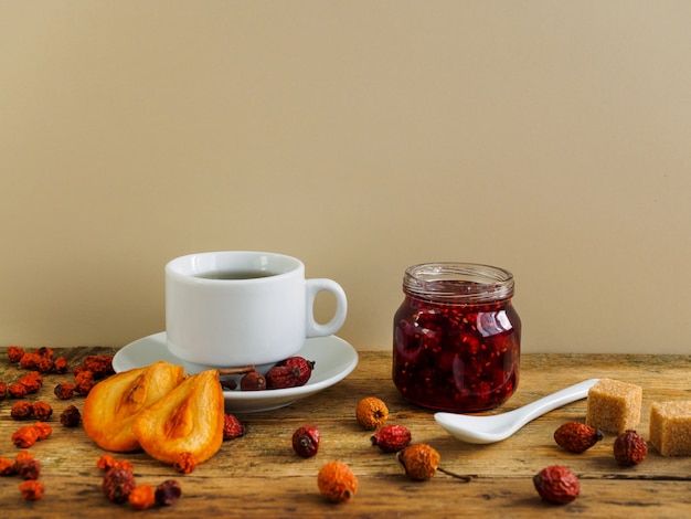 Tisane, confiture et fruits secs sur fond jaune.