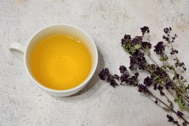 tisane dans une tasse avec des plantes de marjolaine sèches, gros plan