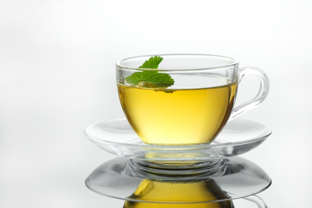 Tisane jaune dans une tasse avec des feuilles de thé chaud fraîchement infusé en gros plan sur fond blanc