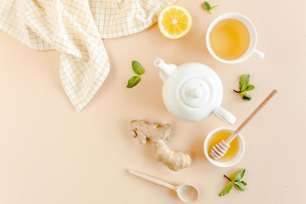 Tisane à la menthe gingembre citron miel et autres herbes sur fond jaune vue de dessus à plat